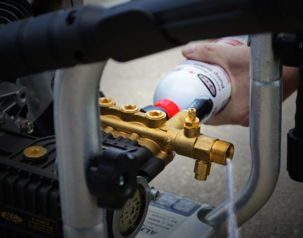 A man screwing on pump guard to a water inlet on a SIMPSON® pressure washer pump