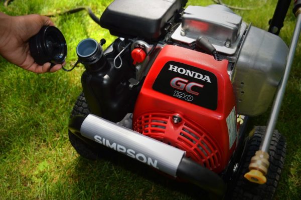 A person putting the gas cap on a SIMPSON® premium pressure washer