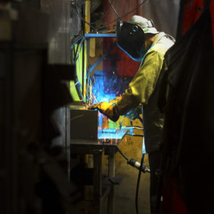 A SIMPSON® pressure washer factory worker wearing a full face mask using a blowtorch