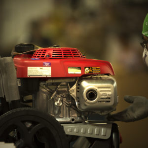A worker inspecting a SIMPSON premium pressure washer with their hand